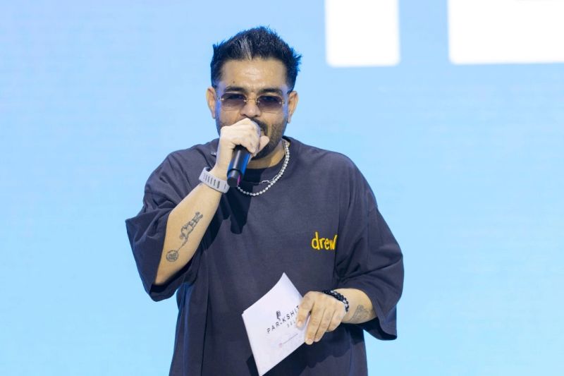 Parikshit hosting a live event with a microphone and cue cards